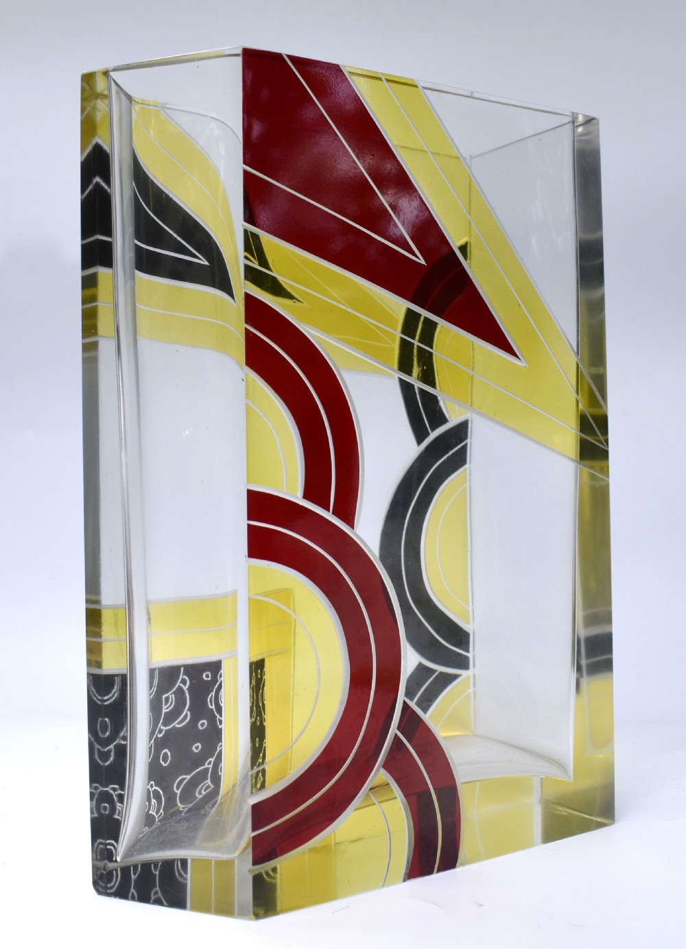 A rectangular clear glass Art Deco vase decorated with etched patterns and enamelled geometric shapes in black, yellow, and red. View V