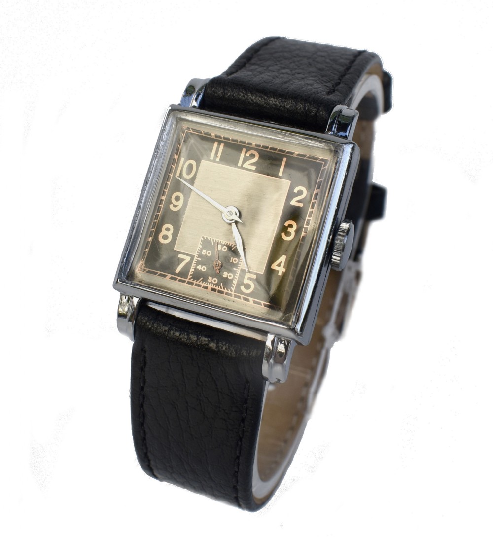 An Art Deco gentlemens wristwatch circa 1935 featuring a rectangular silver-toned case, a black two-tone dial with metallic Arabic numerals, a subdial at six oclock, and a black leather strap. View XI