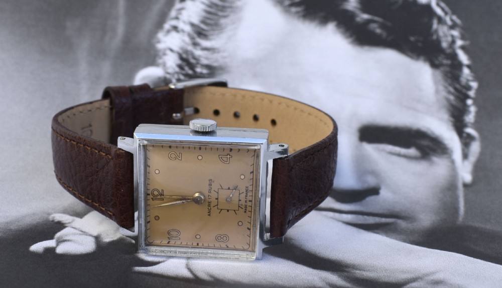 An Art Deco gents mechanical wristwatch featuring a square silver-toned case, cream dial with Arabic numerals, and a brown leather strap. View II