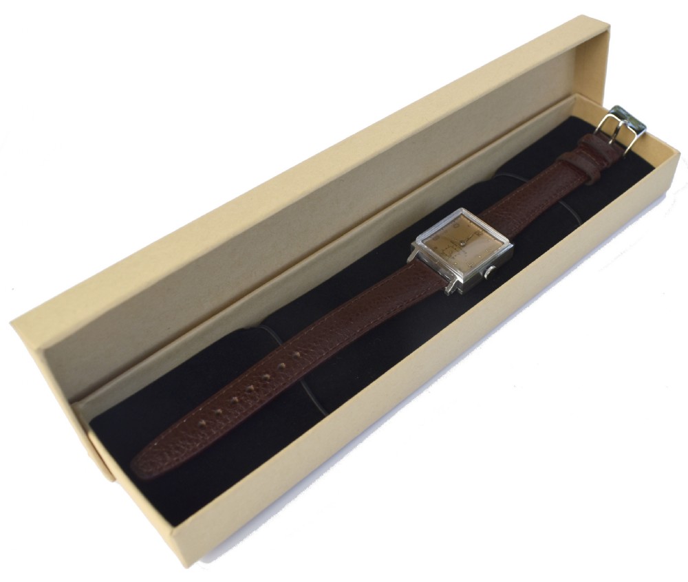 An Art Deco gents mechanical wristwatch featuring a square silver-toned case, cream dial with Arabic numerals, and a brown leather strap. View III