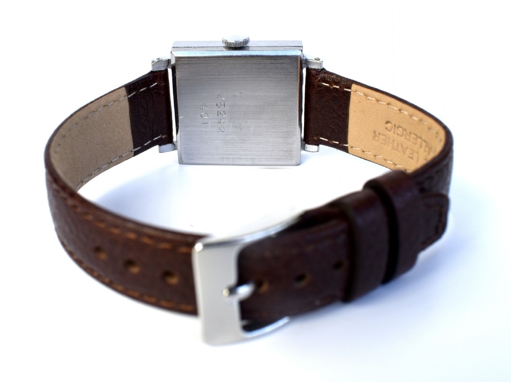 An Art Deco gents mechanical wristwatch featuring a square silver-toned case, cream dial with Arabic numerals, and a brown leather strap. View VI