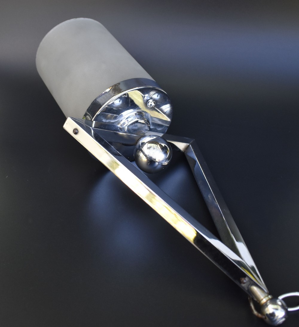 An Art Deco pendant ceiling light featuring a polished chrome triangular suspension frame and spherical detailing above a cylindrical frosted glass shade. View VII