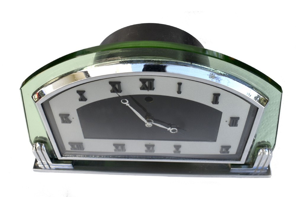 An Art Deco arched green glass mantel clock featuring a chrome frame and black Roman numerals on a two-tone dial. View II