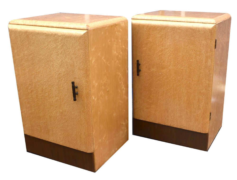A matching pair of 1930s Art Deco bedside cabinets crafted from light blonde maple veneer with dark brown plinth bases and dark vertical door handles. View III