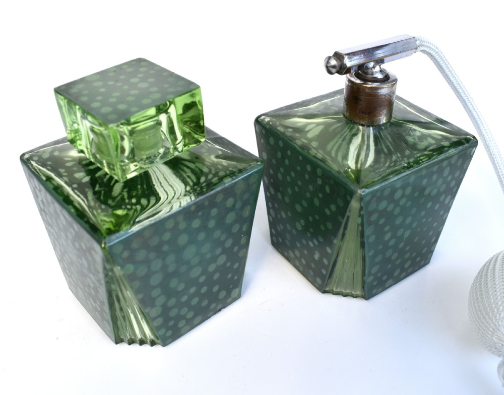 A pair of green Art Deco glass perfume bottles featuring a polka dot pattern, one with a glass stopper and the other with a chrome atomiser pump.