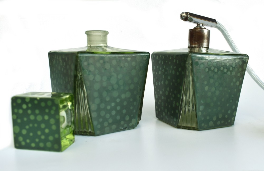 A pair of green Art Deco glass perfume bottles featuring a polka dot pattern, one with a glass stopper and the other with a chrome atomiser pump. View IV