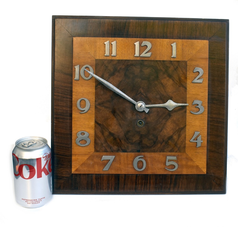 Square Art Deco walnut wall clock featuring layered wood veneers, stylized metal numerals, and metal clock hands. View II