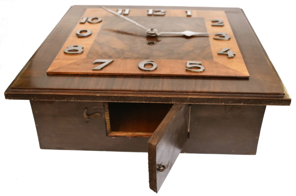 Square Art Deco walnut wall clock featuring layered wood veneers, stylized metal numerals, and metal clock hands. View VII