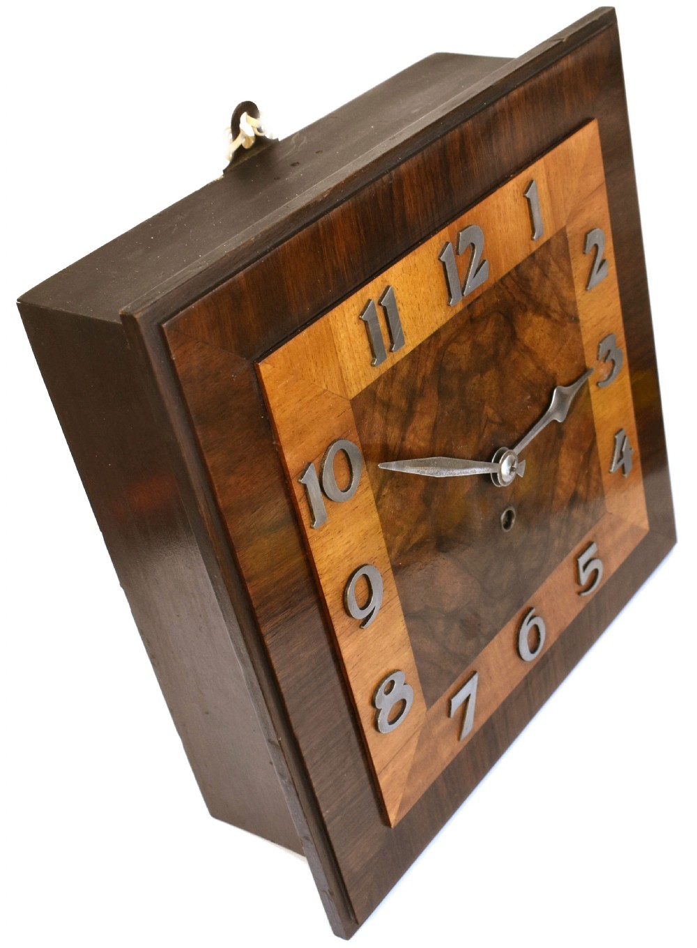Square Art Deco walnut wall clock featuring layered wood veneers, stylized metal numerals, and metal clock hands. View VIII