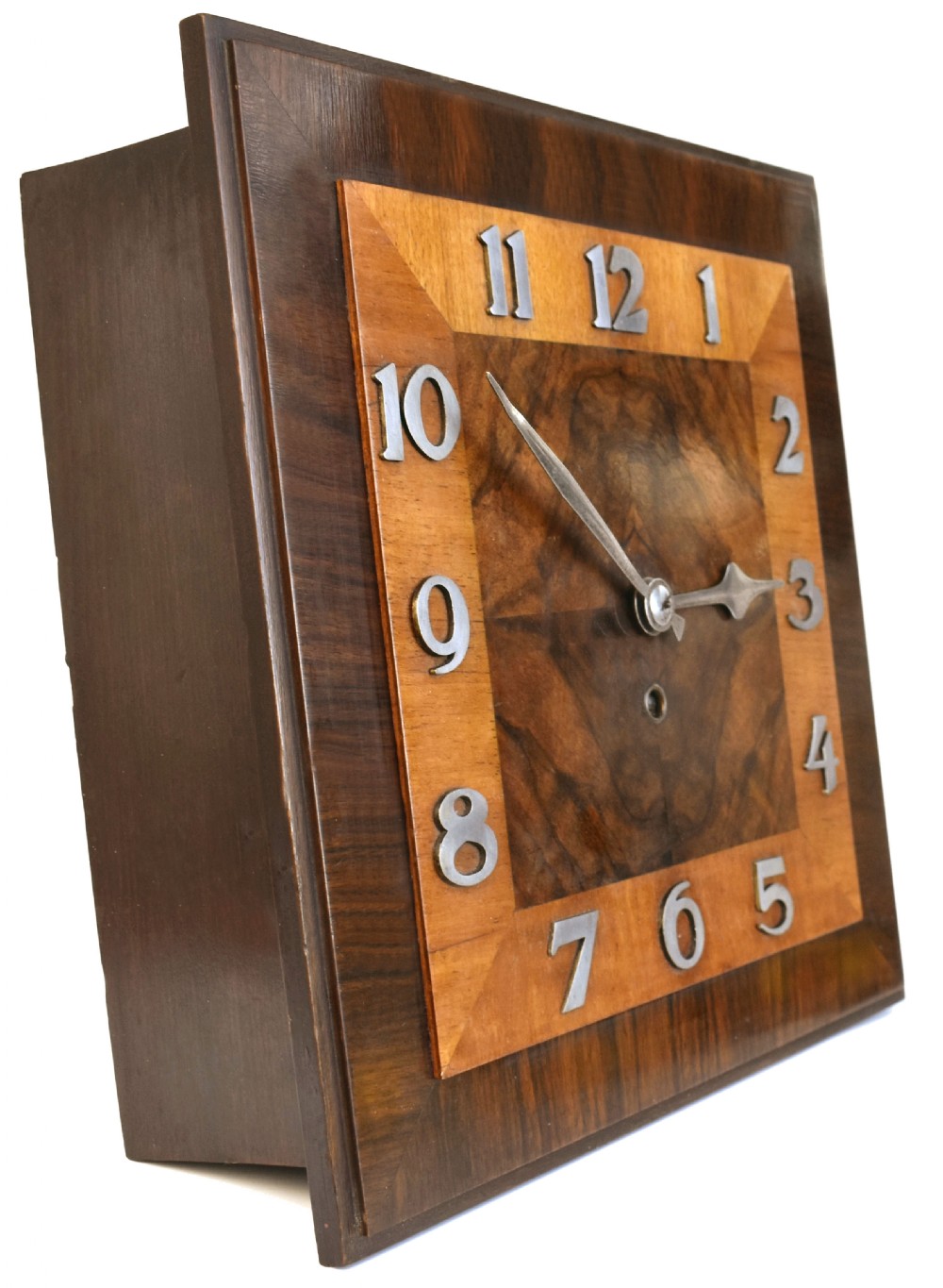 Square Art Deco walnut wall clock featuring layered wood veneers, stylized metal numerals, and metal clock hands. View IX