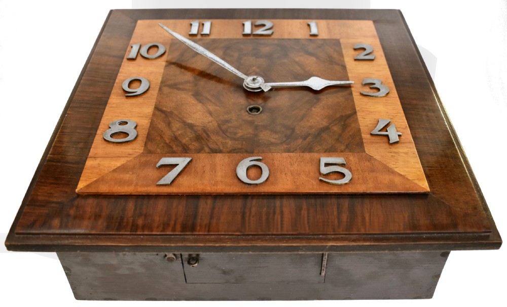 Square Art Deco walnut wall clock featuring layered wood veneers, stylized metal numerals, and metal clock hands. View X