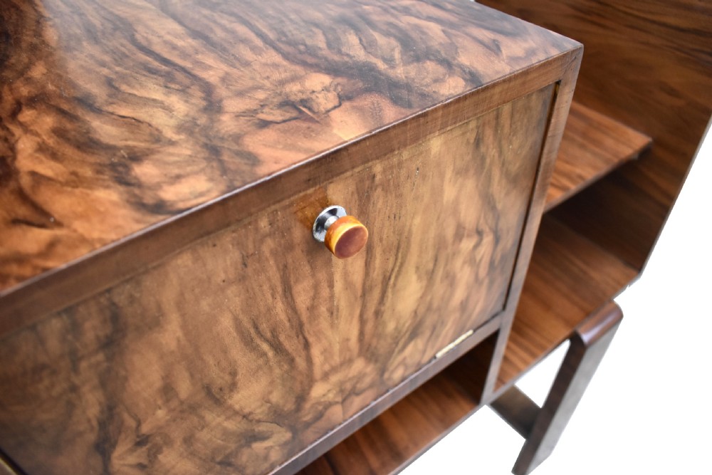 An Art Deco walnut telephone table featuring asymmetrical shelving, a small drop-down cabinet with figured grain, and straight slab legs, circa 1930. View VI