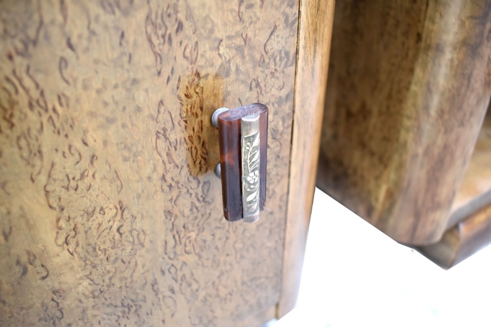 A matching pair of 1930s Art Deco burr elm bedside cabinets featuring top drawers, open compartments, single-door cupboards, and rounded plinth bases. View V