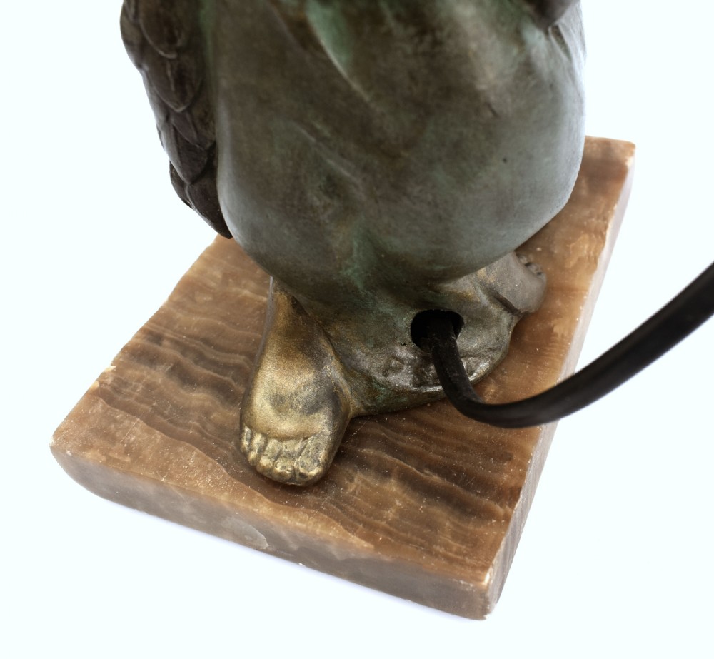 An Art Deco patinated metal table lamp featuring a kneeling female figure holding up a floral garland shade, set on a rectangular marble base. View VII