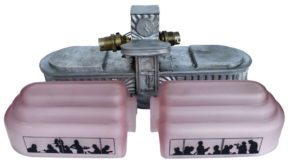 An Art Deco style lamp featuring a stepped pink frosted glass body decorated with black silhouetted figures dining inside windows, framed by a silver-coloured cast metal base and central architectural doorway with a clock motif. View VIII