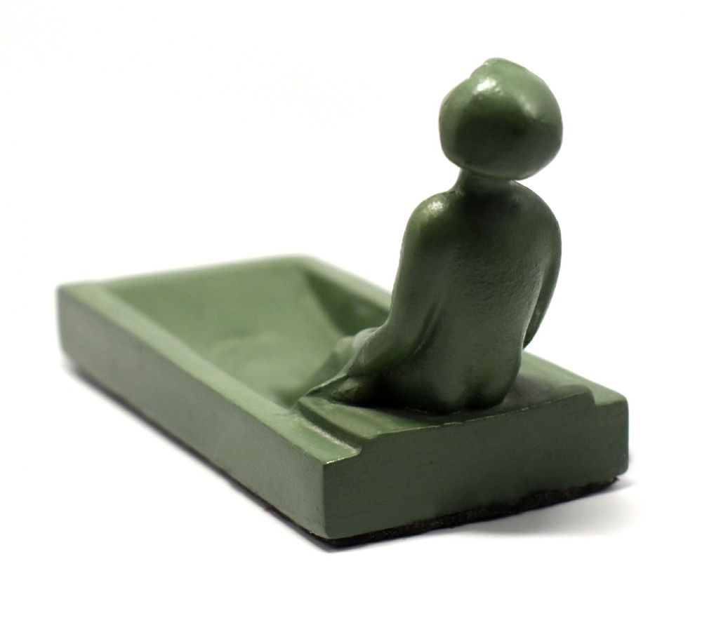 A green Art Deco spelter pin dish featuring a reclining female figure resting along the edge of a small rectangular tray. View VI