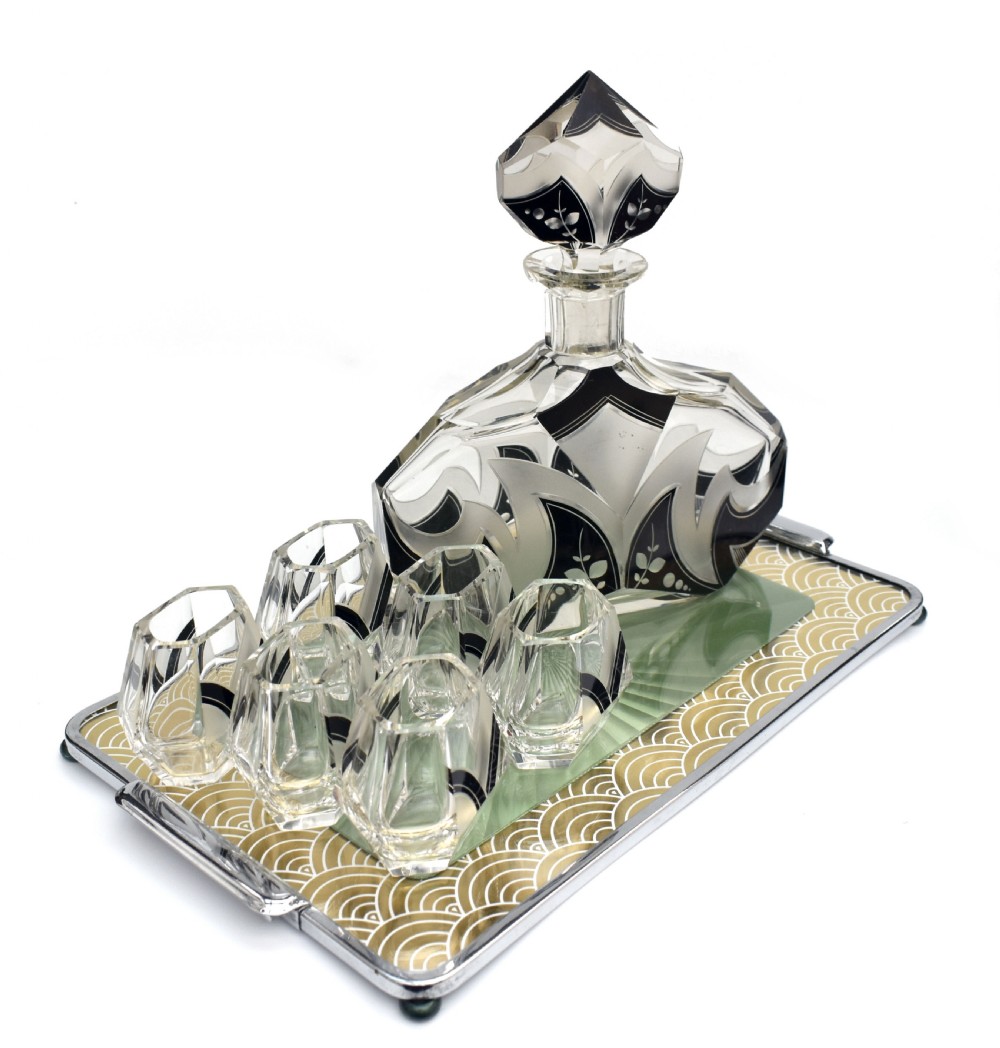 An Art Deco clear glass decanter set featuring black enamelled geometric patterns and frosted accents, accompanied by six matching faceted glasses and a faceted stopper. View IV
