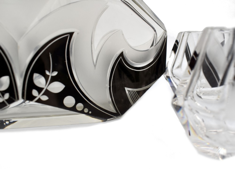 An Art Deco clear glass decanter set featuring black enamelled geometric patterns and frosted accents, accompanied by six matching faceted glasses and a faceted stopper. View V