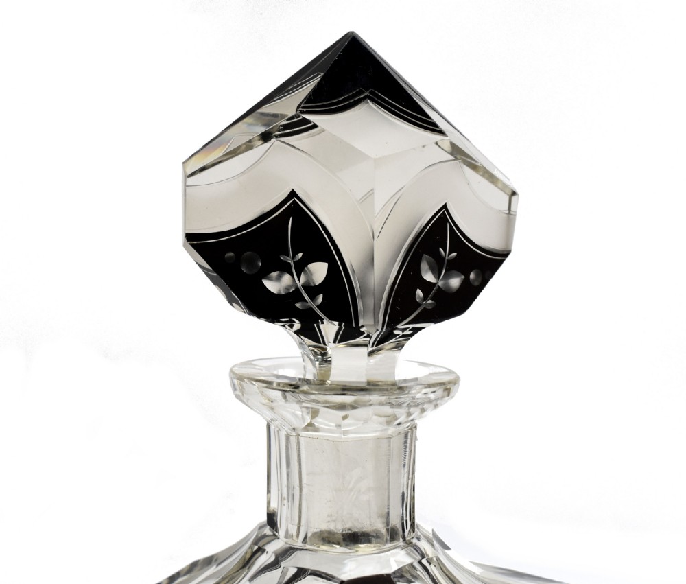 An Art Deco clear glass decanter set featuring black enamelled geometric patterns and frosted accents, accompanied by six matching faceted glasses and a faceted stopper. View VI