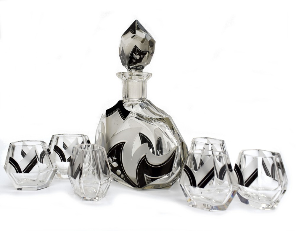 An Art Deco clear glass decanter set featuring black enamelled geometric patterns and frosted accents, accompanied by six matching faceted glasses and a faceted stopper. View VIII