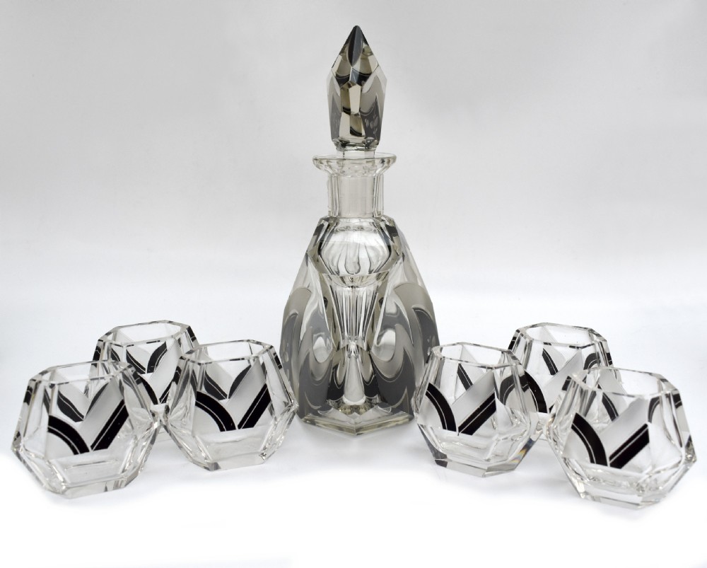 An Art Deco clear glass decanter set featuring black enamelled geometric patterns and frosted accents, accompanied by six matching faceted glasses and a faceted stopper. View IX