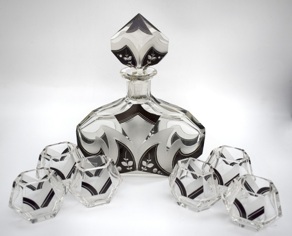 An Art Deco clear glass decanter set featuring black enamelled geometric patterns and frosted accents, accompanied by six matching faceted glasses and a faceted stopper. View XI