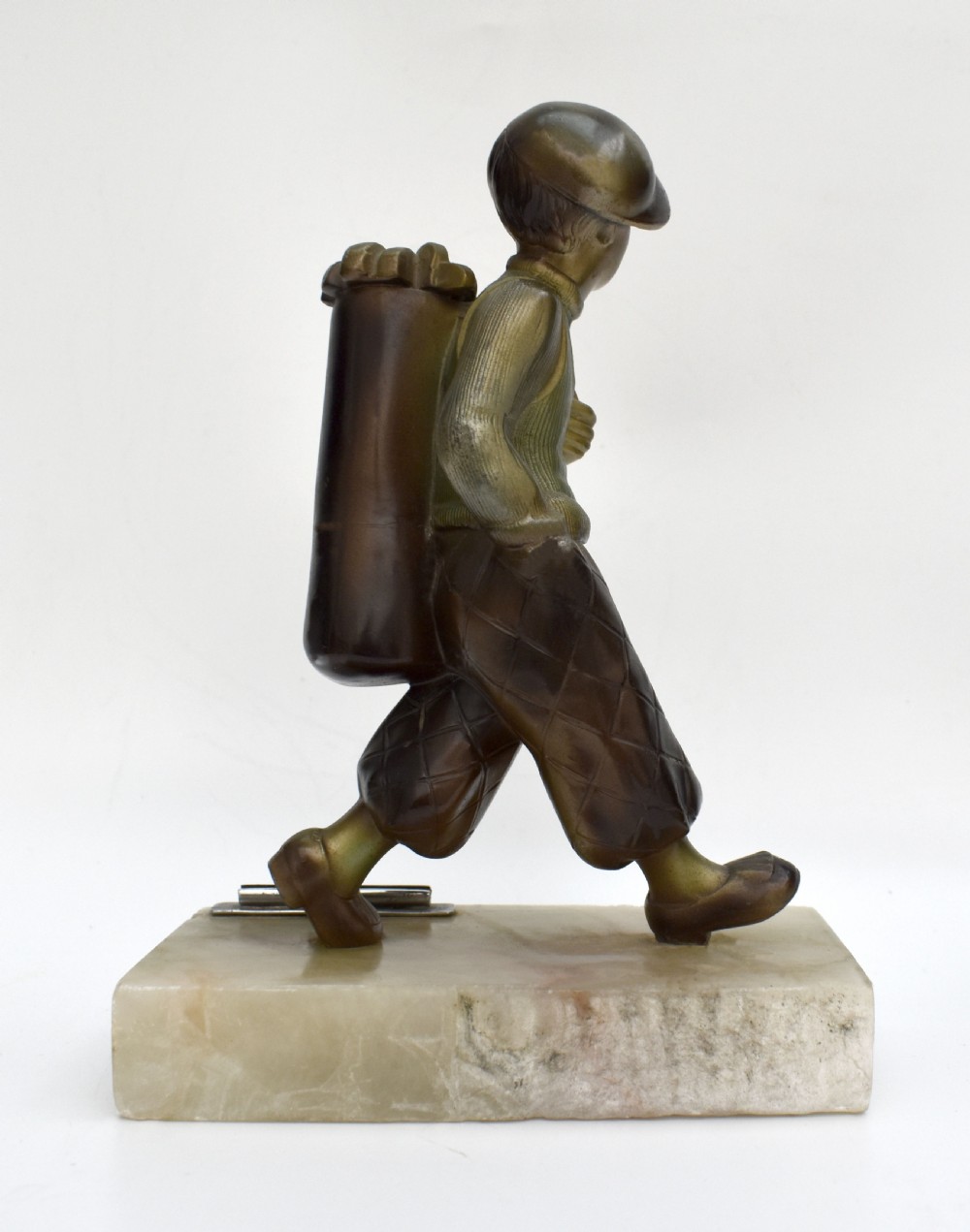 An Art Deco cold-painted bronze sculpture of a golf caddy carrying a bag, mounted on a rectangular cream onyx base with an attached metal lighter striker. View IV