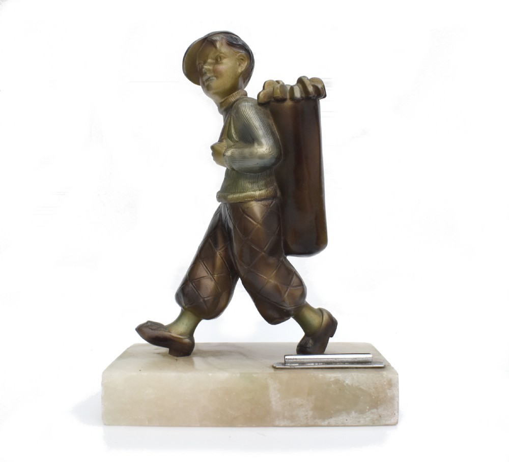 An Art Deco cold-painted bronze sculpture of a golf caddy carrying a bag, mounted on a rectangular cream onyx base with an attached metal lighter striker. View V