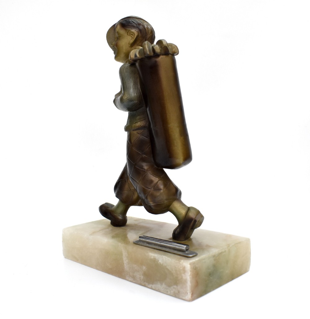 An Art Deco cold-painted bronze sculpture of a golf caddy carrying a bag, mounted on a rectangular cream onyx base with an attached metal lighter striker. View VI