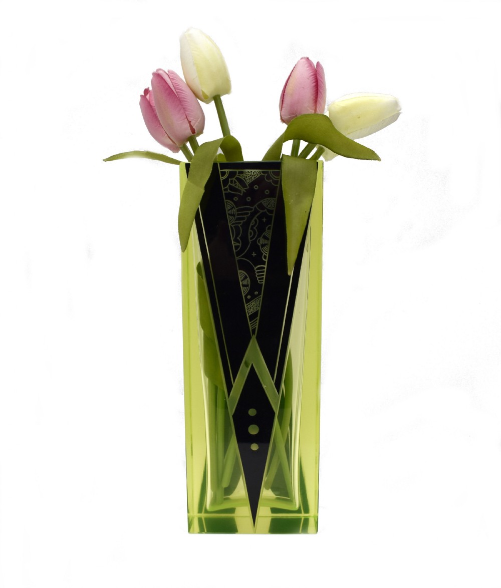 A tall rectangular yellow-green glass vase featuring black geometric Art Deco enamel patterns.