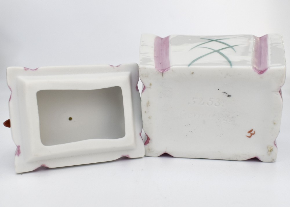 An Art Deco German porcelain trinket box featuring a hand-painted jester figure sitting atop a geometric patterned lidded base. View VII