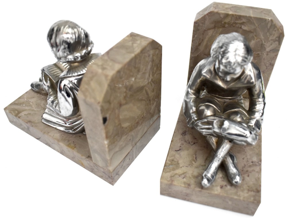 A pair of French Art Deco chromed metal bookends featuring seated children reading, mounted on beige marble bases. View V