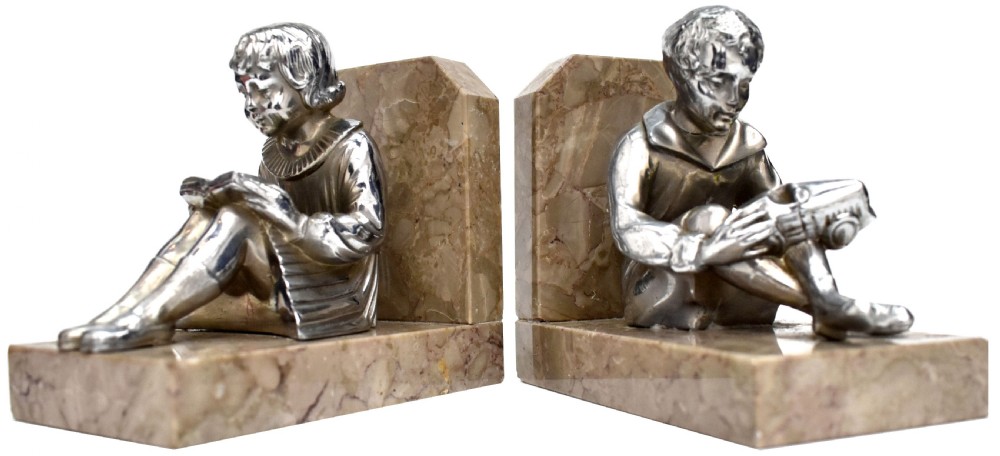 A pair of French Art Deco chromed metal bookends featuring seated children reading, mounted on beige marble bases. View VI