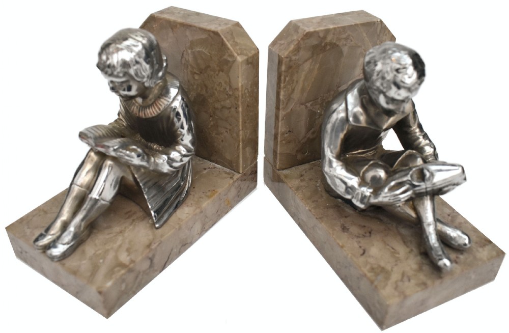 A pair of French Art Deco chromed metal bookends featuring seated children reading, mounted on beige marble bases. View VII