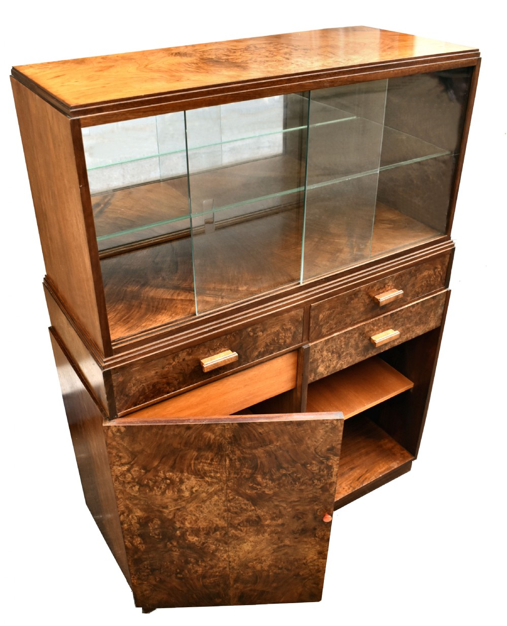 An Art Deco figured walnut drinks cabinet featuring a glass-fronted upper display section with glass shelves, drawers, and lower storage compartments. View III