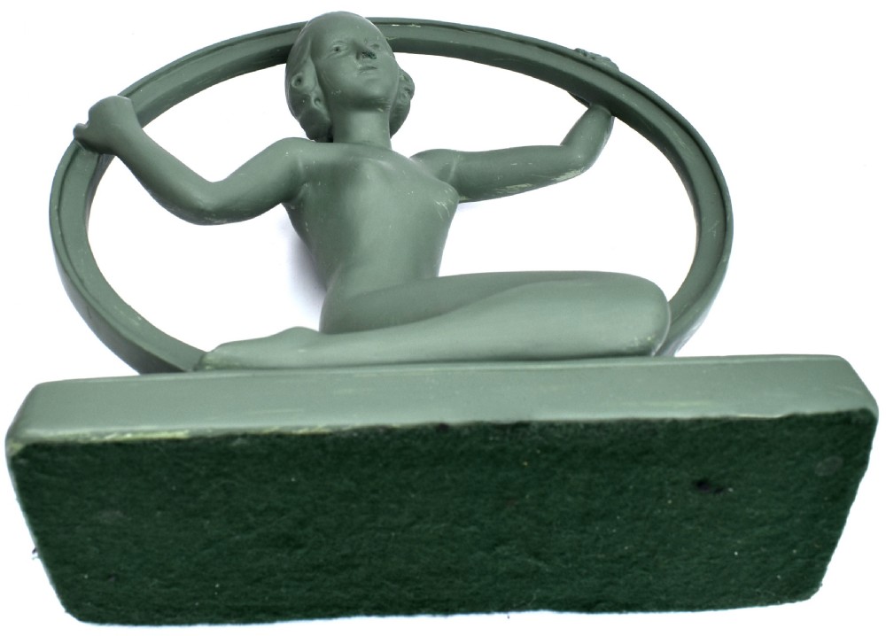 A sage green Art Deco painted plaster figurine depicting a kneeling female figure inside a circular hoop set on a rectangular base. View VIII