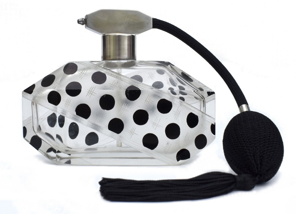 An Art Deco faceted clear glass perfume atomizer featuring black enamel polka dots, crosshatch etchings, a silver-toned metal mount, and a black fabric squeeze bulb with a tassel.