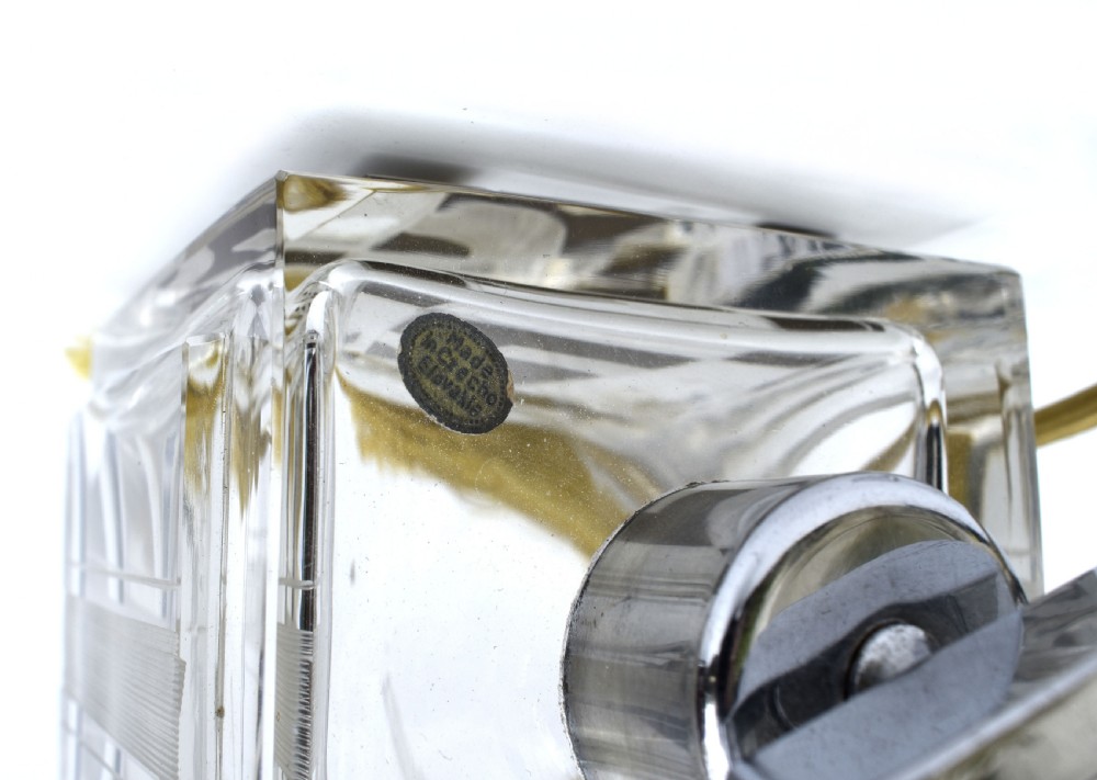 A square clear glass perfume atomizer featuring geometric gold decoration, a chrome pump mechanism, and a gold woven spray tube with a tassel. View V