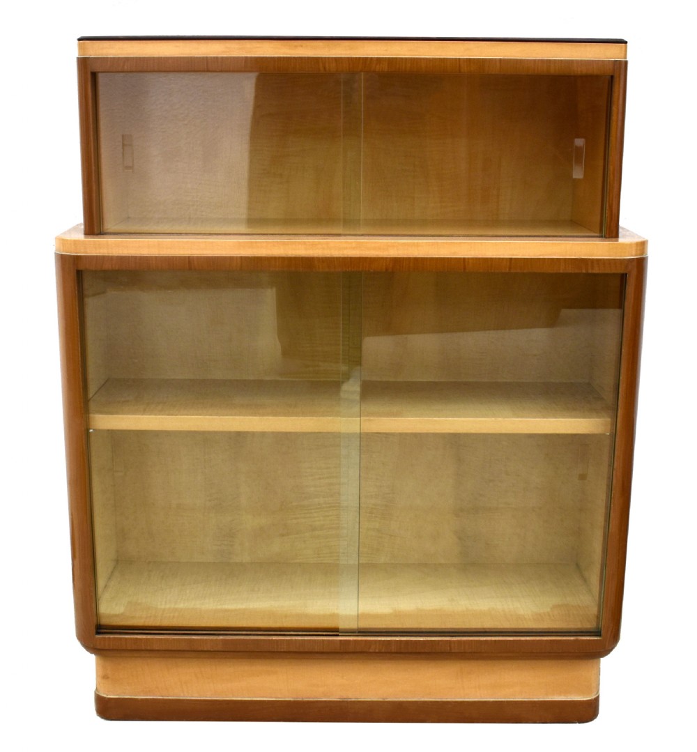 A two-tier Art Deco glazed bookcase constructed from contrasting light sycamore and dark walnut veneers with sliding glass doors.
