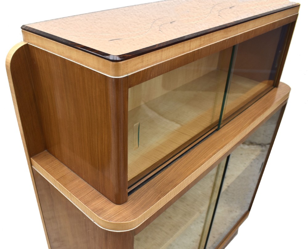 A two-tier Art Deco glazed bookcase constructed from contrasting light sycamore and dark walnut veneers with sliding glass doors. View V