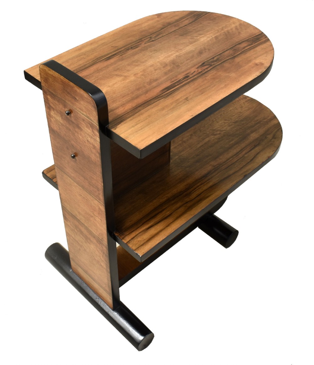 A two-tier Art Deco modernist walnut side table featuring curved cantilevered shelves, ebonised trim, and cylindrical base supports. View VI