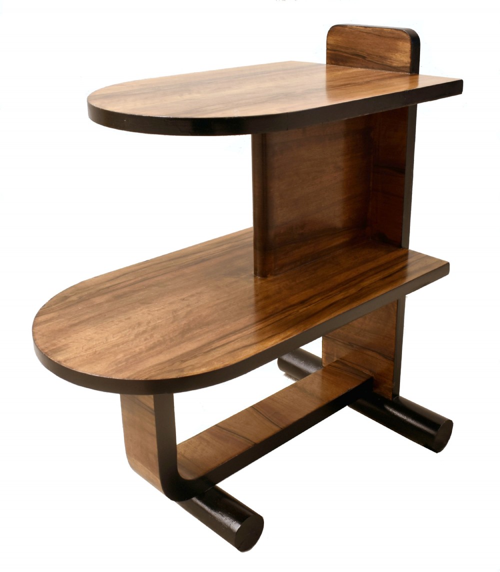 A two-tier Art Deco modernist walnut side table featuring curved cantilevered shelves, ebonised trim, and cylindrical base supports.