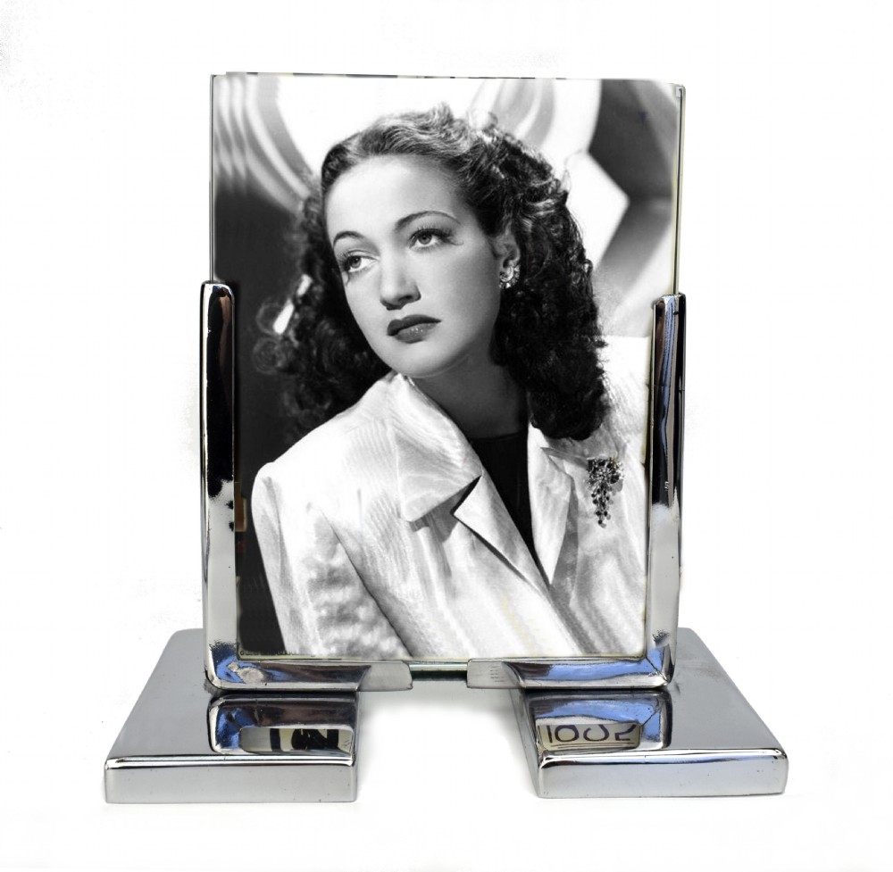 An Art Deco chrome and glass free-standing picture frame featuring a stepped metal base holding a black and white portrait photo.