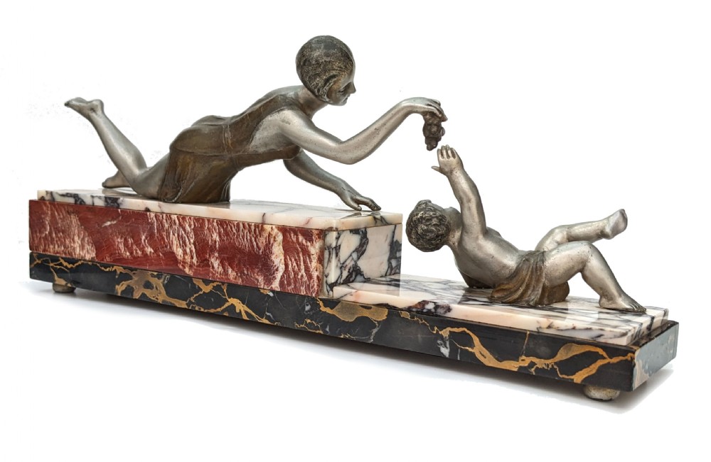An Art Deco French spelter figural group depicting a reclining mother reaching towards her child on a stepped marble base. View VI
