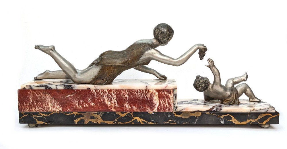 An Art Deco French spelter figural group depicting a reclining mother reaching towards her child on a stepped marble base. View VII