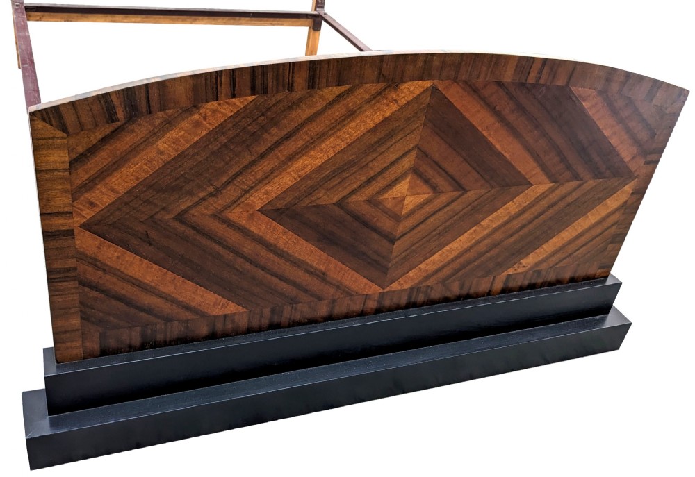 An Art Deco walnut double bed frame featuring an arched headboard and footboard with geometric diamond veneering on a dark stepped base. View VI