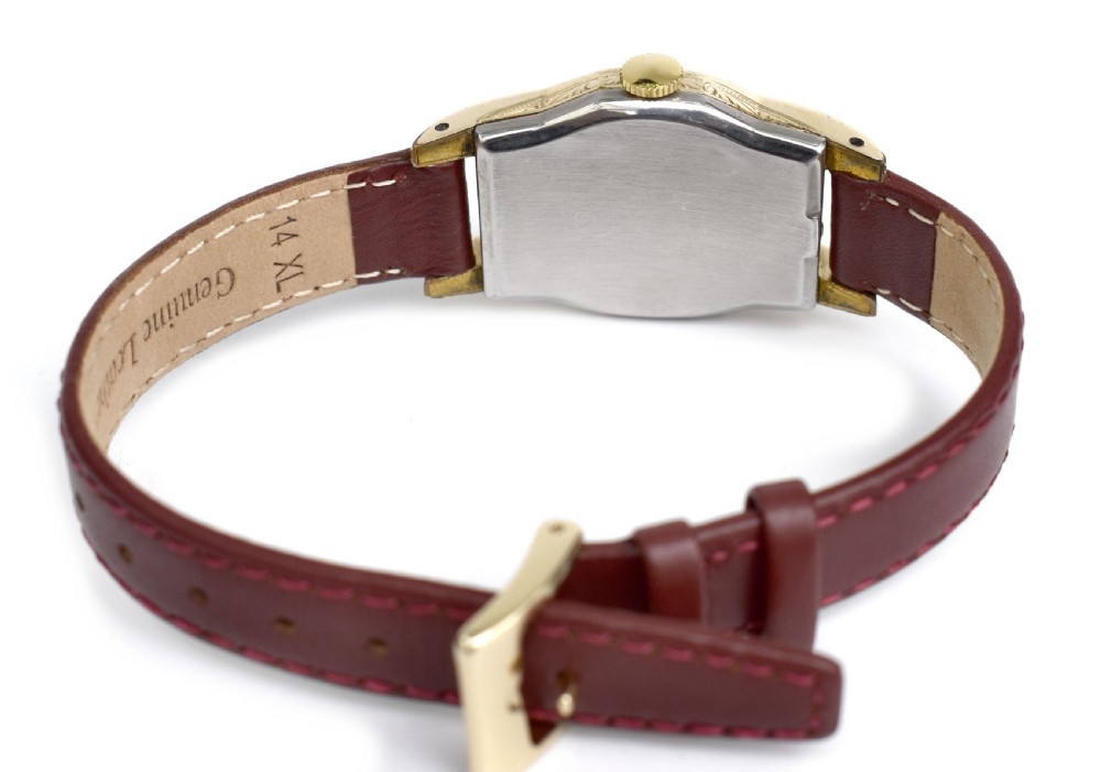 An Art Deco Bulova gents wristwatch featuring a gold-tone tonneau case with engraved side detailing, a cream dial with gold numerals, and a burgundy leather strap. View V