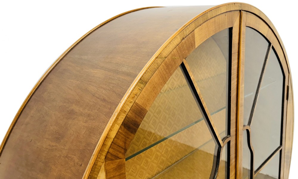 An Art Deco circular walnut display cabinet featuring two glazed doors with geometric astragal glazing bars and interior glass shelves. View V