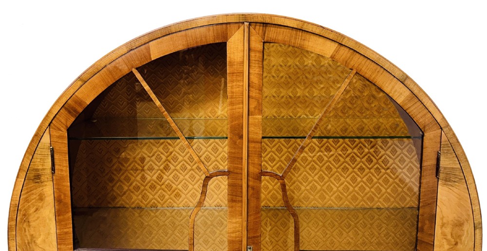 An Art Deco circular walnut display cabinet featuring two glazed doors with geometric astragal glazing bars and interior glass shelves. View VIII