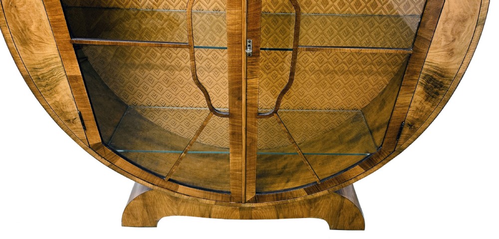 An Art Deco circular walnut display cabinet featuring two glazed doors with geometric astragal glazing bars and interior glass shelves. View XIII